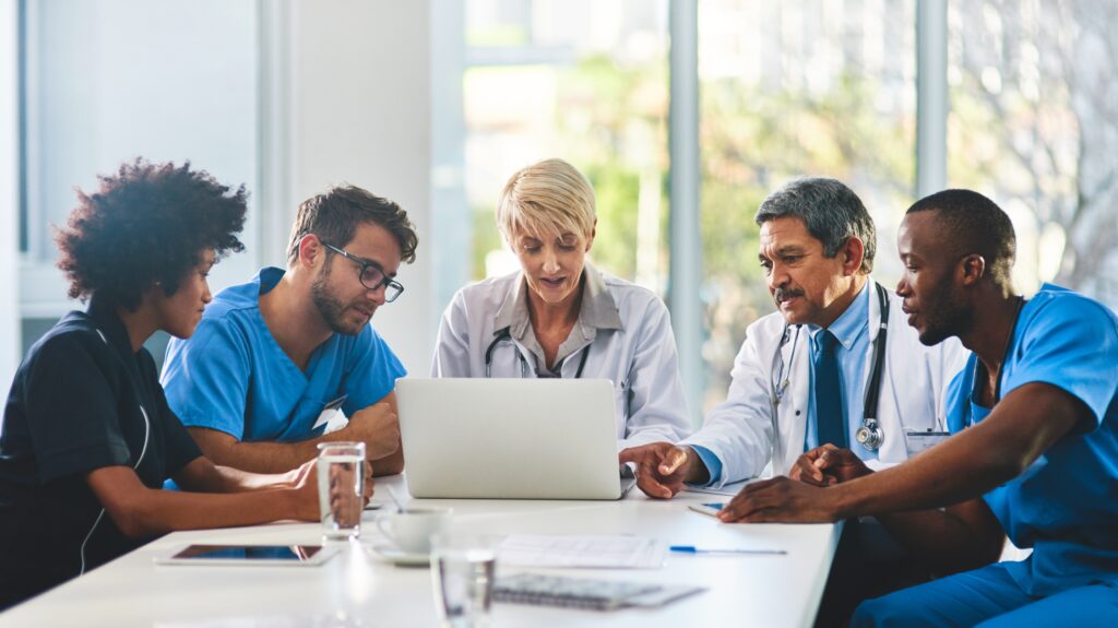 Healthcare professionals sitting around a table looking at a computer